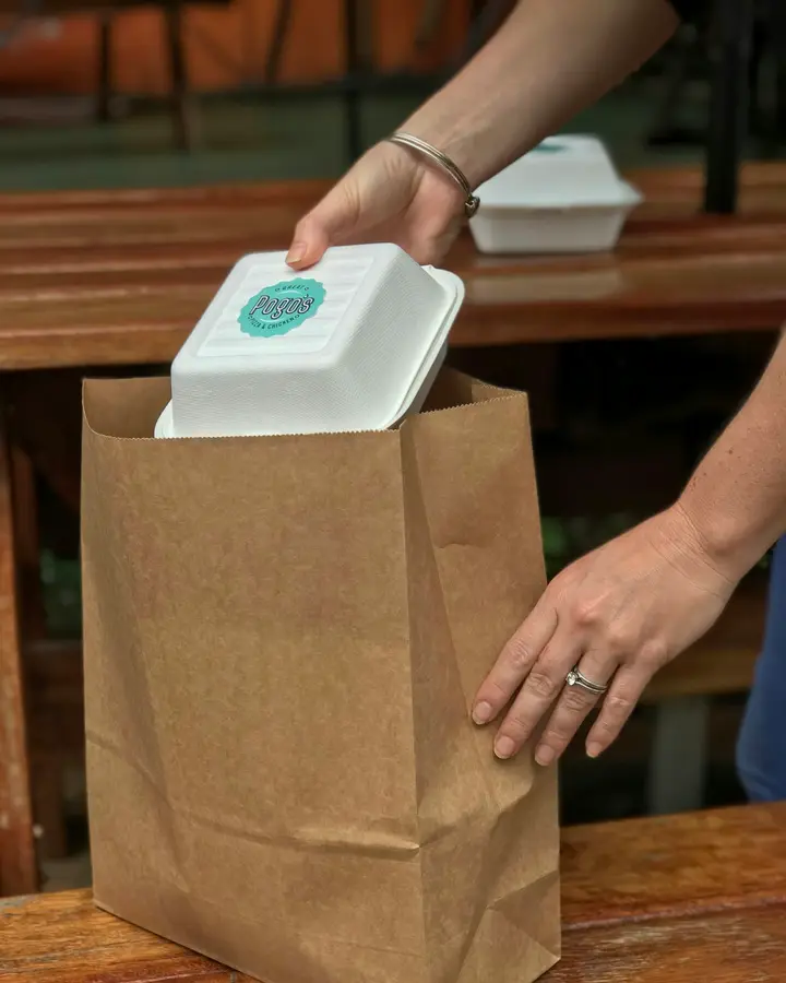 Manos guardando un pedido de comida en una bolsa de papel