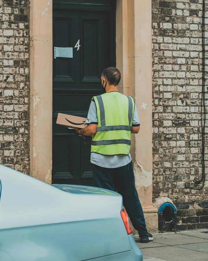 Repartidor llevando un paquete a la puerta de una casa