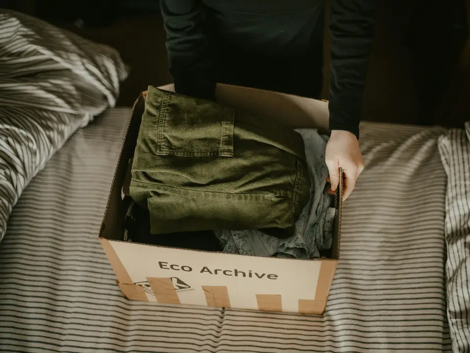 Manos acomodando prendas dentro de una caja de envío