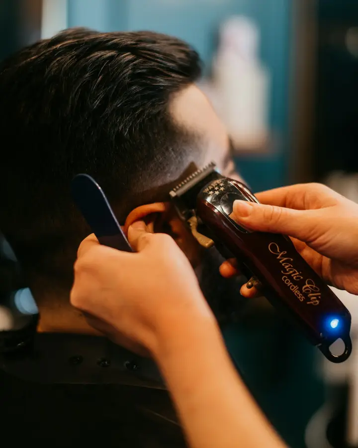 Barbero perfilando un corte con la máquina